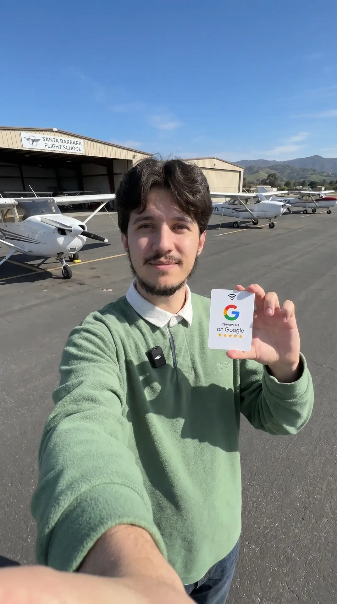 Flight school instructor holding an NFC Google review card