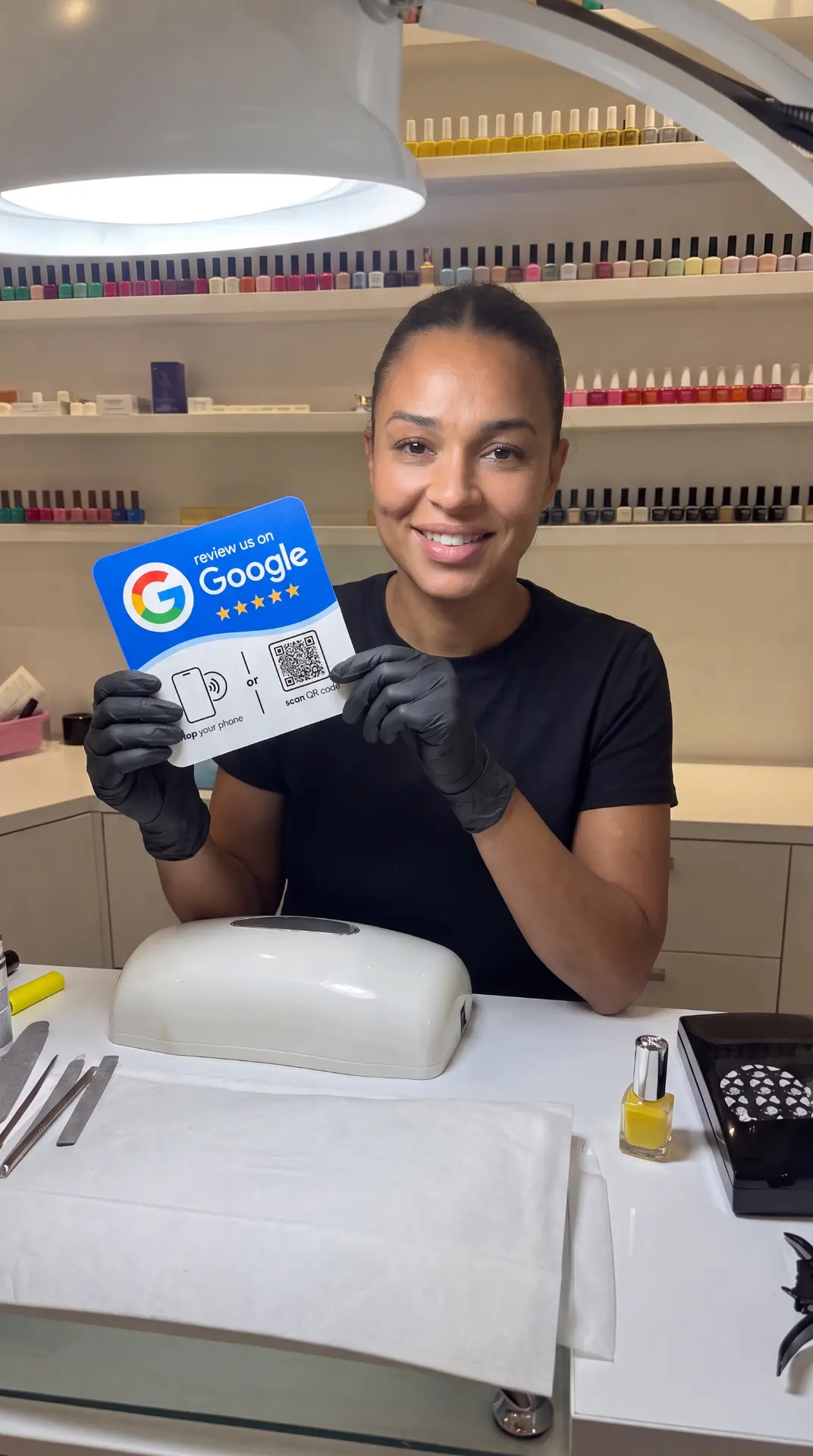 Nail technician holding a Google review NFC sign